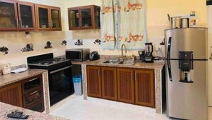 Cozinha com armários de madeira, geladeira de aço inoxidável, micro-ondas, pia e fogão.