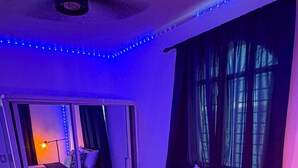 Ein Schlafzimmer mit Bett, Nachttisch, Lampe und einer Schiebetür, die auf einen Balkon führt.