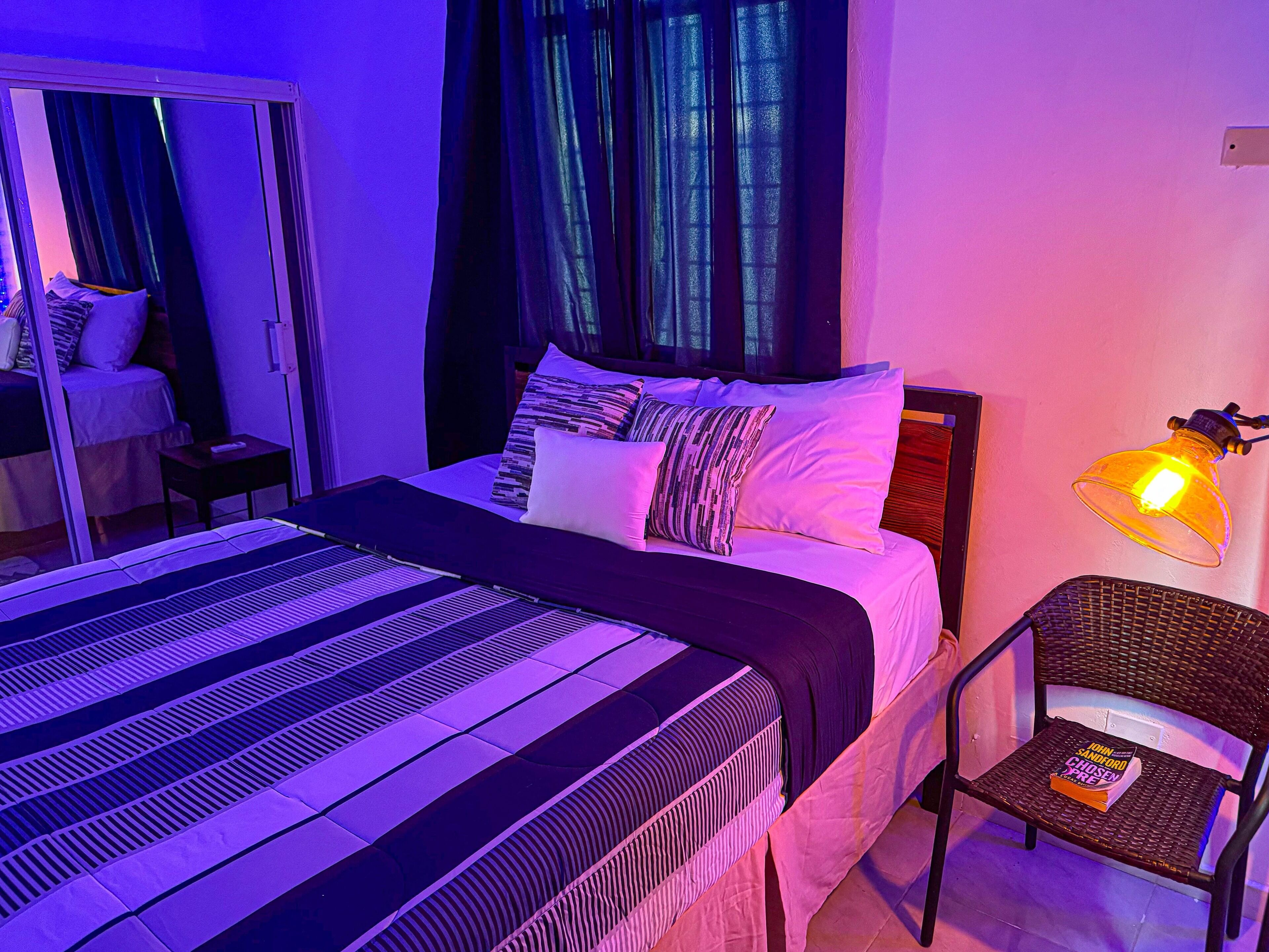 A bedroom with a bed, a chair, a lamp, and a mirror.