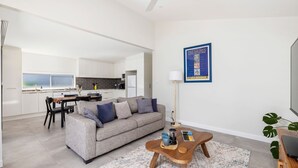 Un salon moderne avec un canapé gris, une table basse et un livre encadré accroché au mur.
