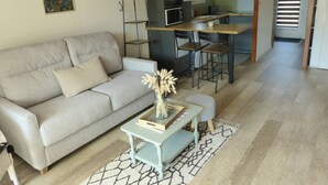 Un salon comprenant un canapé, une table basse et un coin cuisine avec une table à manger et des chaises.