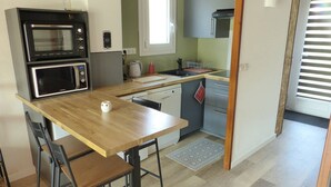 Une cuisine compacte équipée d’un four à micro-ondes, d’un four traditionnel, d’un évier et d’un petit coin repas avec une table et des chaises.