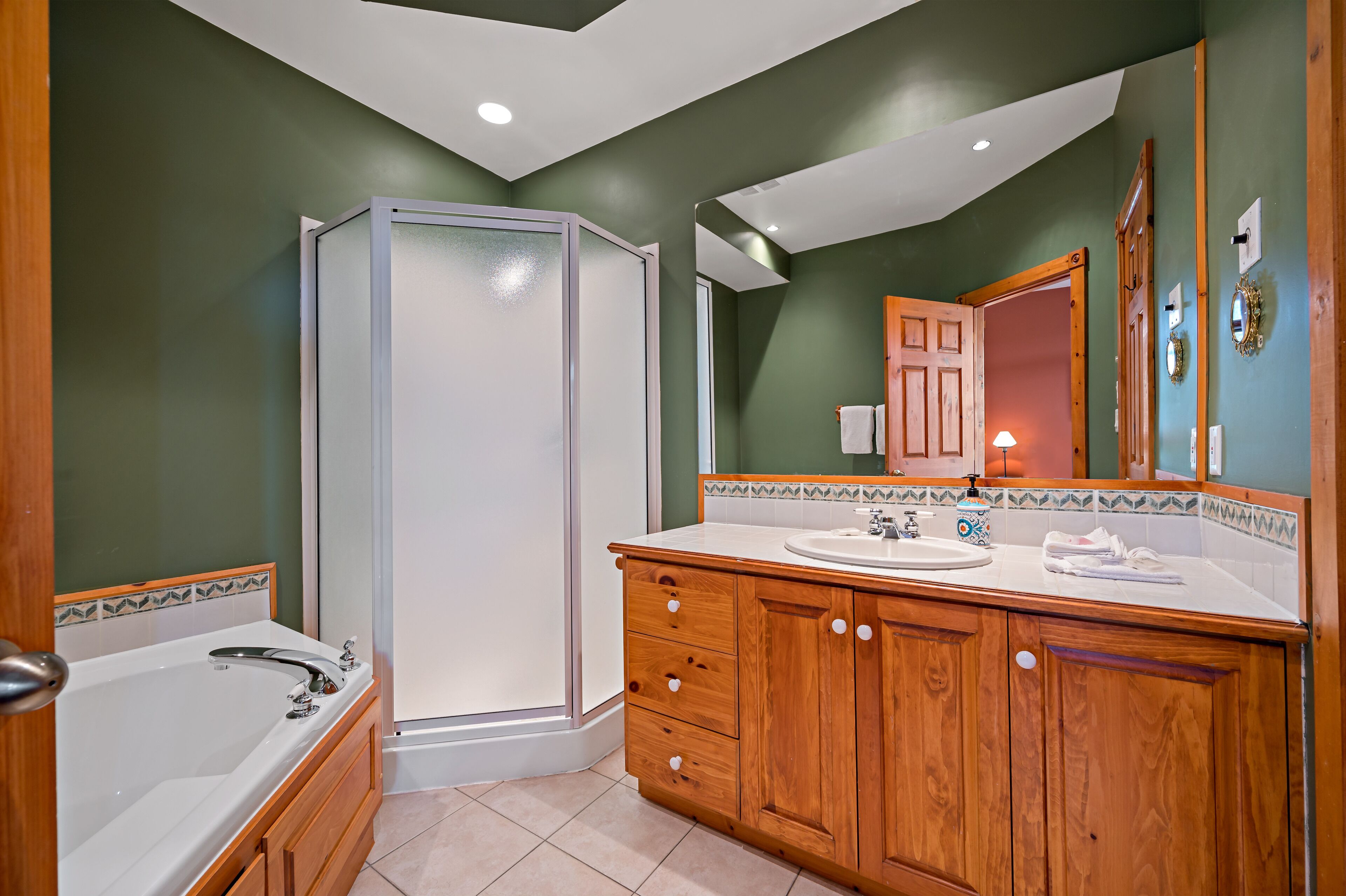 A modern bathroom with a walk-in shower, wooden vanity, and a large mirror.