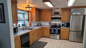 A kitchen with wooden cabinets, a stainless steel refrigerator, a dishwasher, a stove, and a microwave.