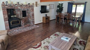 A living room with a brick fireplace, wooden furniture, and a flat-screen TV mounted on the wall.