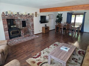 Una sala de estar con chimenea de ladrillo, muebles de madera y un televisor de pantalla plana montado en la pared.