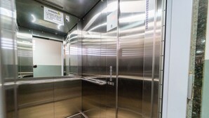 Un ascenseur vide aux parois métalliques, sur lequel est apposé un panneau d’avertissement.