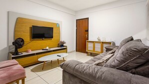Un salon moderne avec un téléviseur à écran plat fixé à un mur en bois, un canapé, une table basse et un petit meuble.