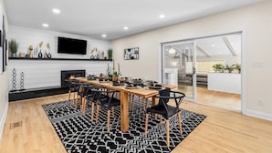 A modern dining area with a wooden table, black chairs, and a black and white patterned rug. - Blue Skies Retreat - Custom-Built Retreat in the Suburbs! (Farmington Hills)