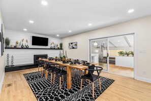 A modern dining area with a wooden table, black chairs, and a black and white patterned rug.