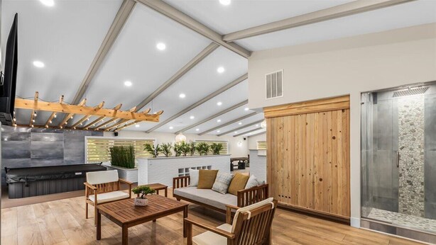 A spacious living area with a wooden ceiling, a built-in fireplace, and a stone wall. - Blue Skies Retreat - Custom-Built Retreat in the Suburbs! (Farmington Hills)