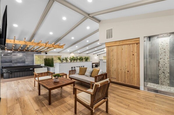A spacious living area with a wooden ceiling, a built-in fireplace, and a stone wall.