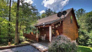 A wooden cabin with a porch, a sign reading "WOODLAND", and a gravel path leading to it.