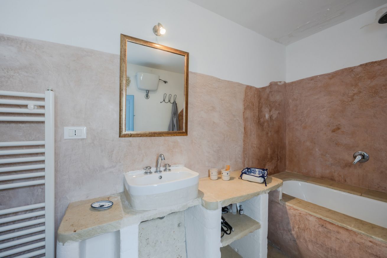 Un baño con un lavabo blanco, un espejo, un toallero y una bañera.