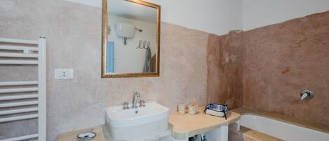 Un baño con un lavabo blanco, un espejo, un toallero y una bañera.