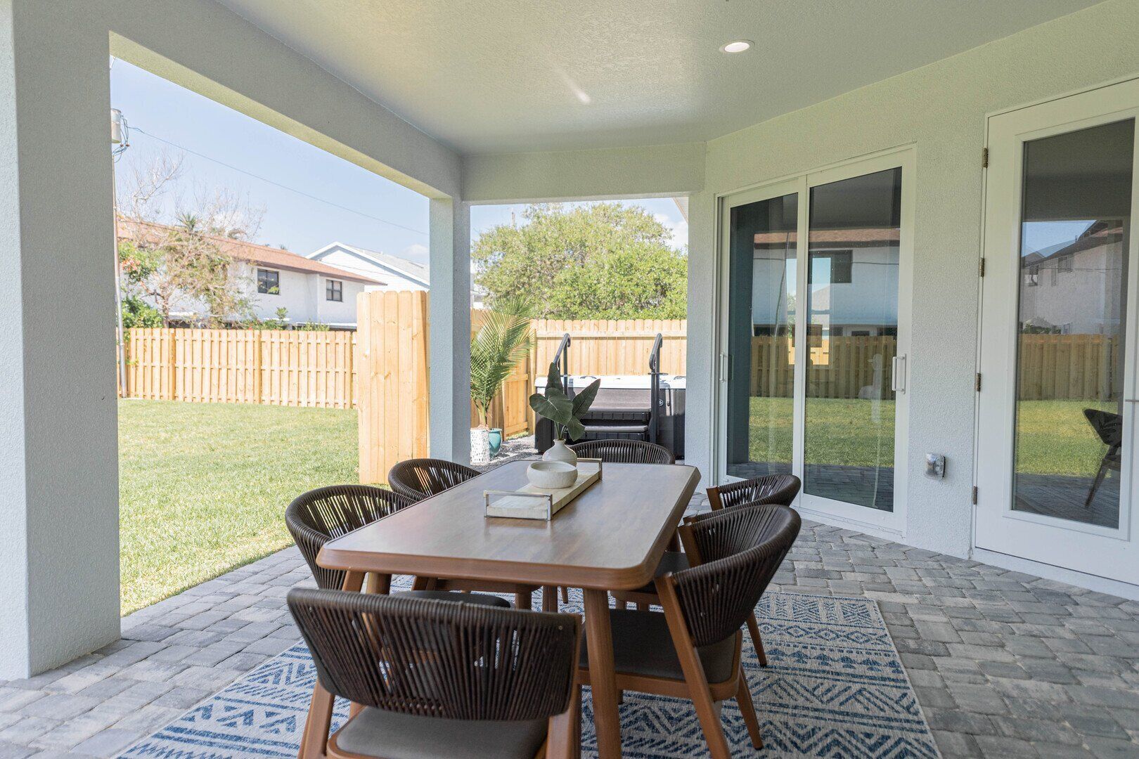 A covered patio with a table and chairs, a grill, and a sliding glass door.