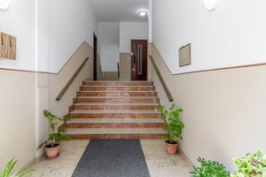 A staircase with a marble finish, flanked by potted plants, leading to a door at the top.