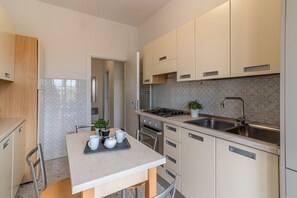 A modern kitchen with a dining table, chairs, a stove, sink, and cabinets. - GuestHost - Apartment located on the third floor of a building equipped with a lift (NOT suitable for the disabled).In 82 square meters of space it comfortably accommodates 7 people.The apartment is located 4 minutes walk from the bus stop, ideal for rea (Ferrara)