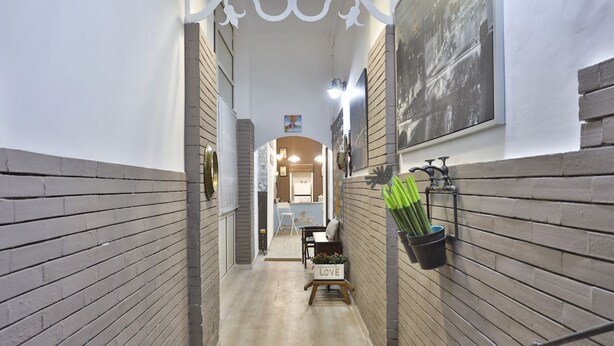 A narrow hallway with a wooden floor, a small table with a sign, and a wall-mounted plant holder.