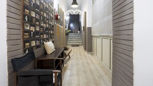 A hallway with a wall-mounted display of numbered items, a bench, and a staircase leading to an upper level.