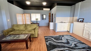 A living room with a green sofa, a coffee table, and a patterned rug. - Ocean View Capitol Hill Studio with Sunset Deck (Capitol Hill)