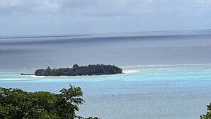 A coastal landscape with a small island surrounded by clear turquoise waters and a cloudy sky. - Ocean View Capitol Hill Studio with Sunset Deck (Capitol Hill)