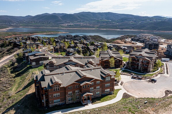 A residential area with multiple houses, a large building with a prominent entrance, and a lake in the background.
