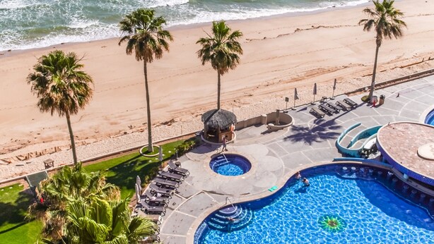 Un complexe hôtelier doté d’une piscine, de palmiers et d’une plage.