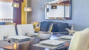 Un coin repas avec une table ronde dressée pour quatre personnes, un bol de biscuits et une étoile de mer décorative.