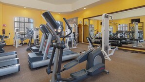 Une salle de sport équipée de machines de cardio, de matériel de musculation et d’un grand miroir.