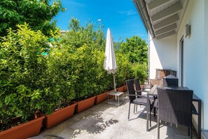 Enjoy an outdoor space surrounded by lush greenery and a shaded table for two.