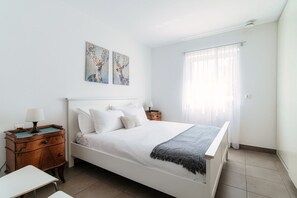 Relax in this serene bedroom with a large bed, nightstand, and wall-mounted artwork.