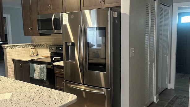 A modern kitchen with stainless steel appliances, wooden cabinets, and a granite countertop. - 3-bedroom vacation home just 9 minutes from Port Canaveral (Merritt Island)