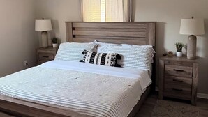 A bedroom with a wooden bed, two bedside tables with lamps, a ceiling fan, and a window with curtains. - 3-bedroom vacation home just 9 minutes from Port Canaveral (Merritt Island)