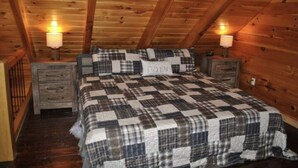 A cozy attic bedroom with a checkered quilt, two bedside lamps, and a wooden ceiling. - Amazing Views! Hot Tub!! Minutes from the Gorge!!! (Stanton)