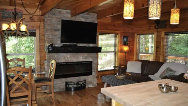 A cozy cabin interior with a stone fireplace, wooden furniture, and large windows. - Amazing Views! Hot Tub!! Minutes from the Gorge!!! (Stanton)