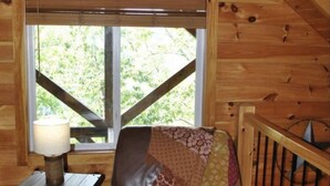 A cozy cabin interior with a leather chair, a small table with a lamp, and a window with a view of greenery. - Amazing Views! Hot Tub!! Minutes from the Gorge!!! (Stanton)