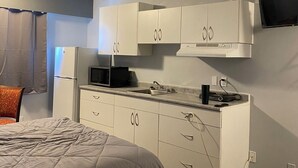 A compact kitchenette with a microwave, stove, and sink. - Nechako Valley Inn  (Vanderhoof)