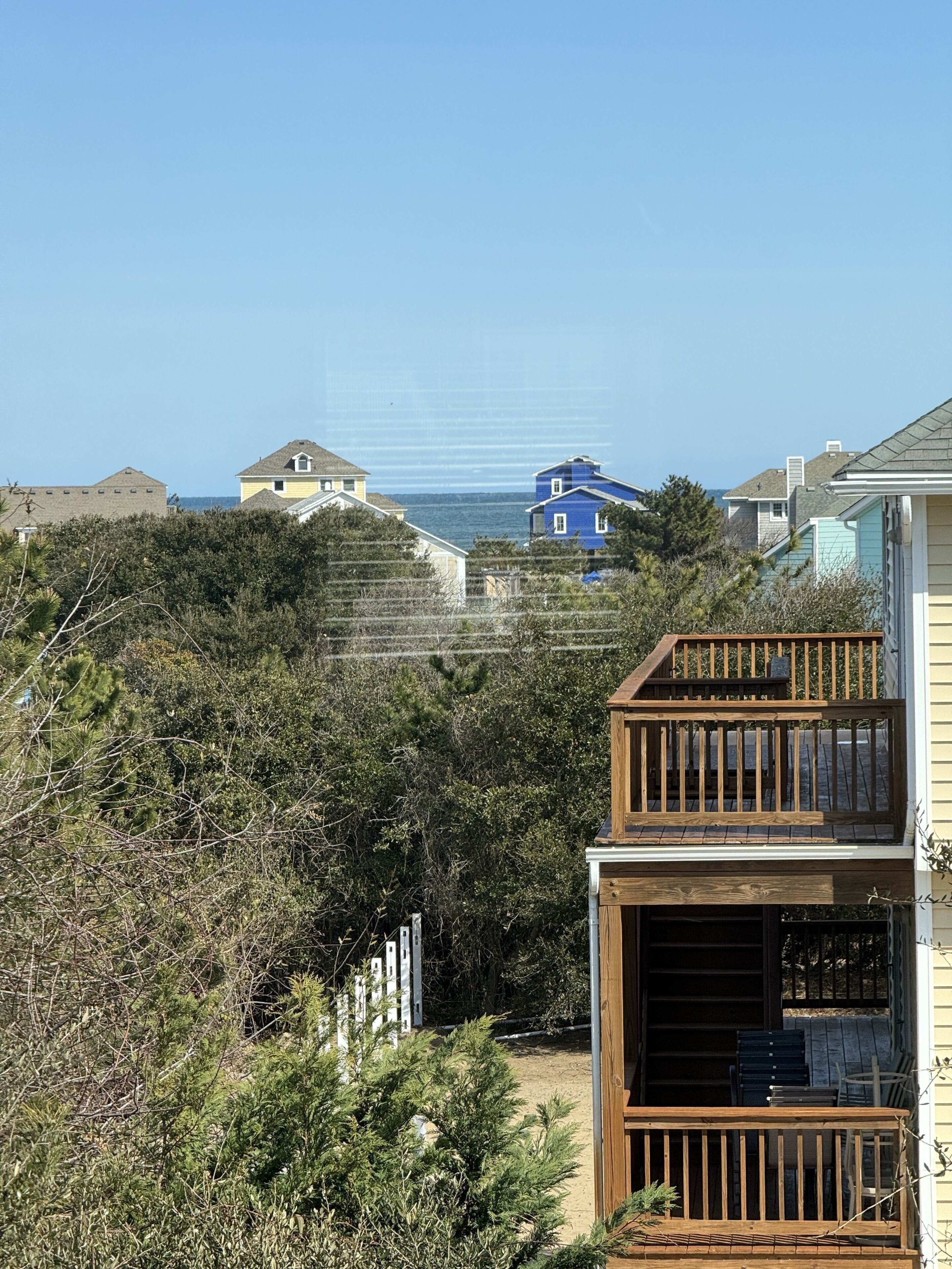 Un quartier résidentiel en bord de mer, avec des maisons, une terrasse en bois et une vue sur l’océan.