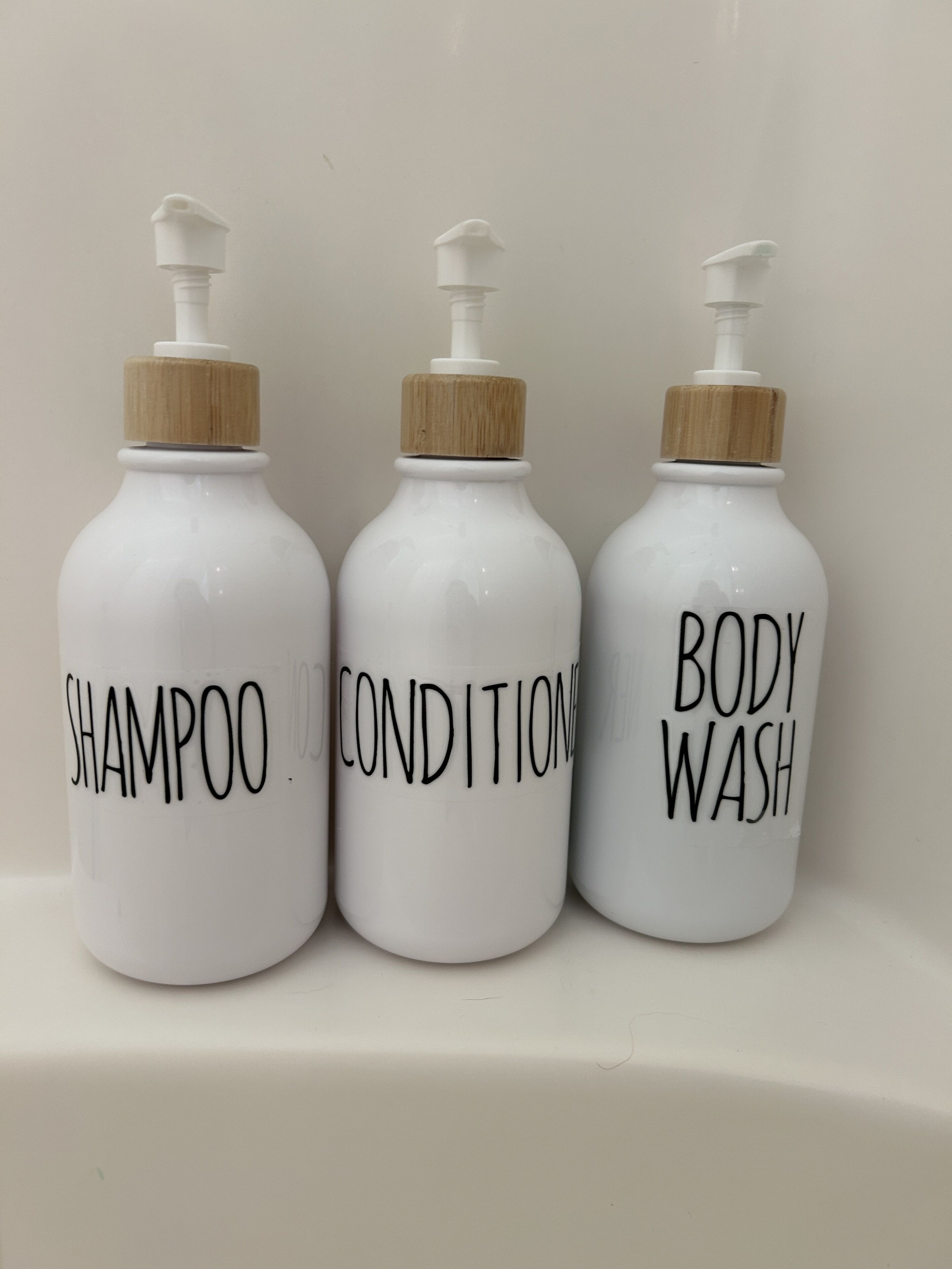 Three white bottles with labels on a white surface.