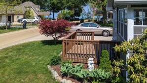A residential area with a house featuring a front deck, a driveway, and a well-maintained lawn. - Cozy Pet Friendly Cottage, Partial Water View, Sleeps 7, Half Block from Beach! (Lexington)