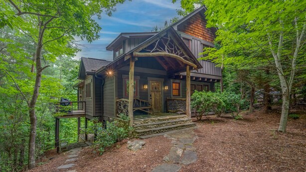 A cabin with a stone pathway leading to the entrance, surrounded by dense forest.