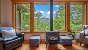 A cozy room with a large window, a wood-burning stove, and a sofa.