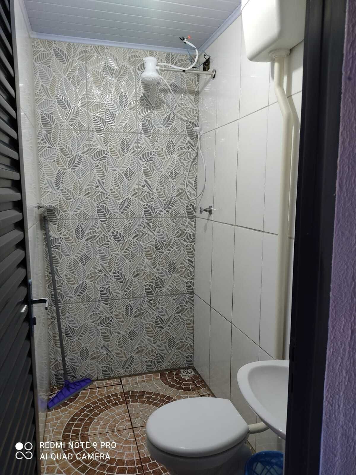 A bathroom with a patterned tile wall, a toilet, and a shower area.