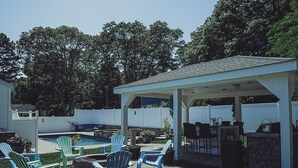A backyard with a covered patio, outdoor seating, a barbecue area, and a swimming pool. - Beach nearby Pool/HotSpa Firepit LGbackyard (Barnstable)