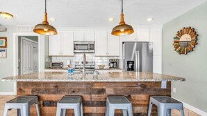 Una cocina con isla central, electrodomésticos de acero inoxidable y un salpicadero de madera rústica.