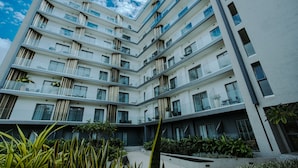 A multi-story building with balconies, large windows, and a courtyard with plants. - The Lennox 802 One Bed Duplex (Accra)