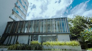 A modern building with large windows and a balcony, surrounded by greenery. - The Lennox 802 One Bed Duplex (Accra)