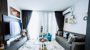 A modern living room with a flat-screen TV, a sofa, a coffee table, and a large window with curtains. - The Lennox 802 One Bed Duplex (Accra)