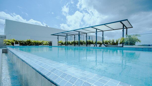 A swimming pool with a covered area and a modern building in the background. - The Lennox 802 One Bed Duplex (Accra)